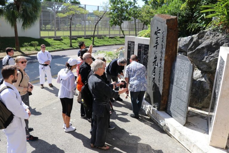 Guided history tour group at a karate monument in Naha