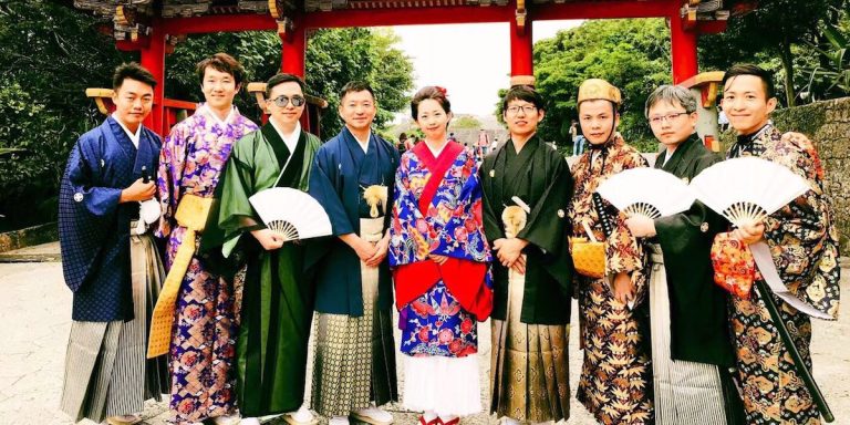 Group in traditional Okinawan costume at a castle gate
