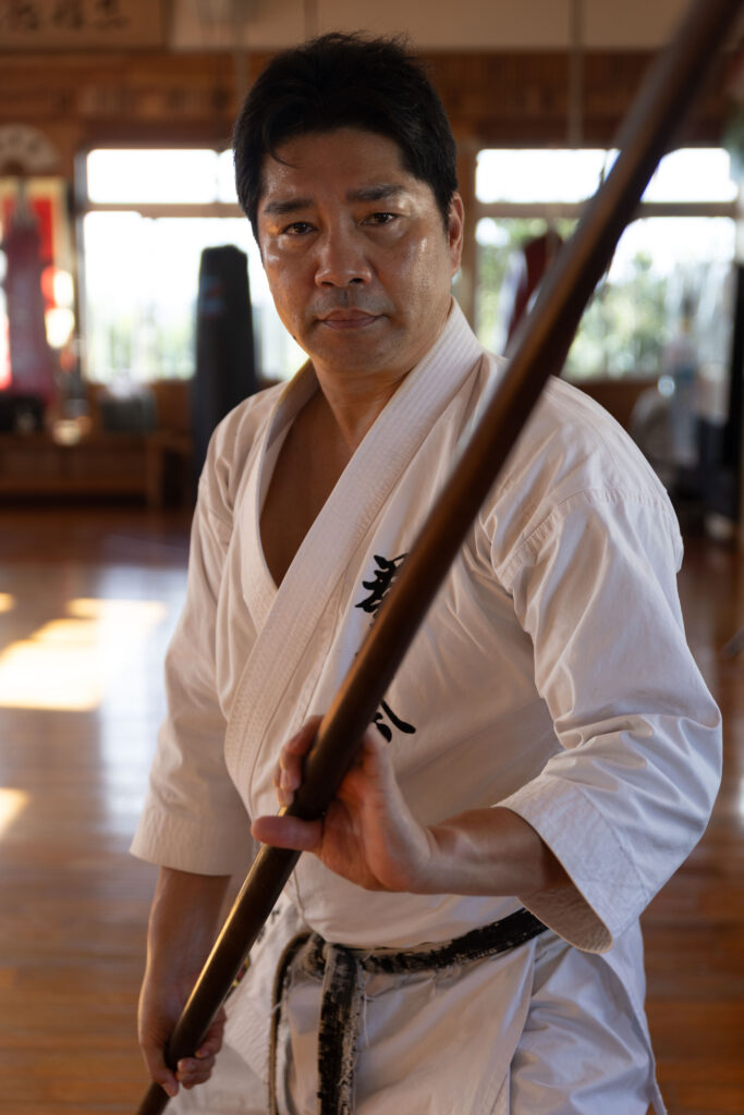 Karateka holding a bo staff in a dojo