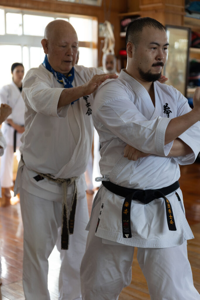 Senior instructor correcting a student's stance in a dojo