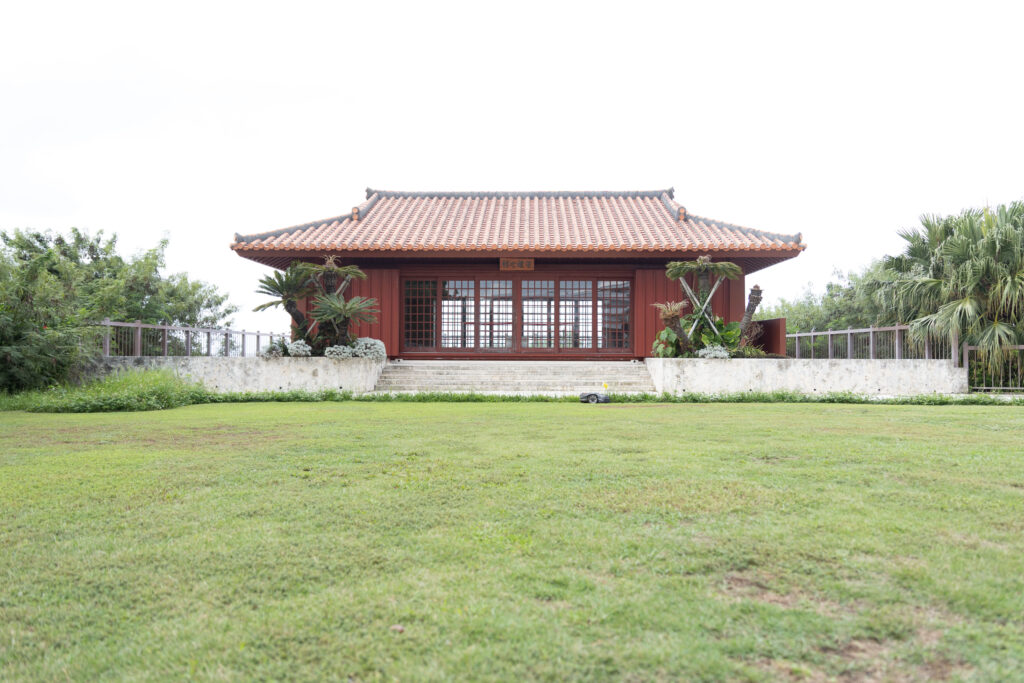 Traditional red-roofed Okinawan hall above a lawn