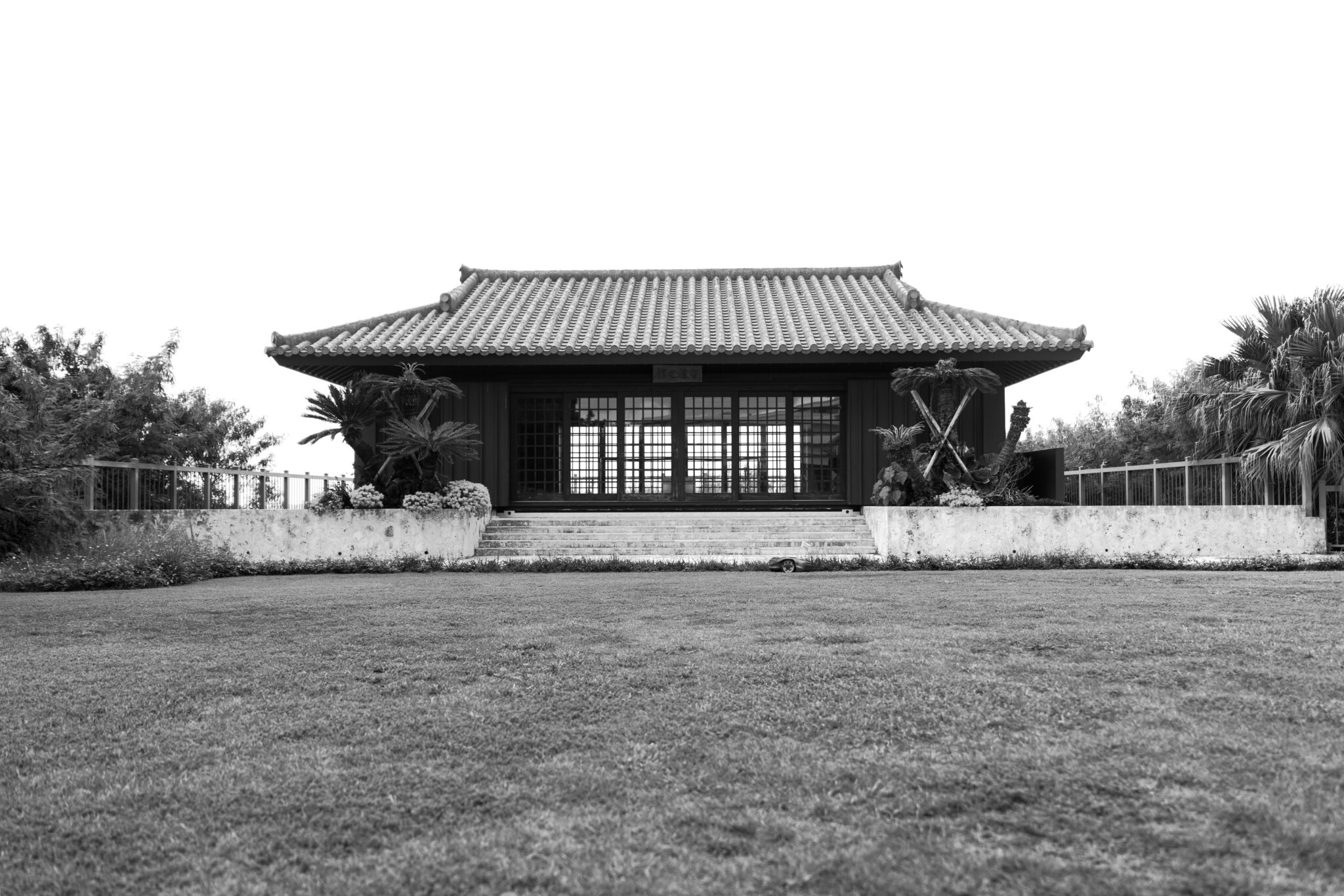 Traditional Okinawan karate hall with a tiled roof, in black and white