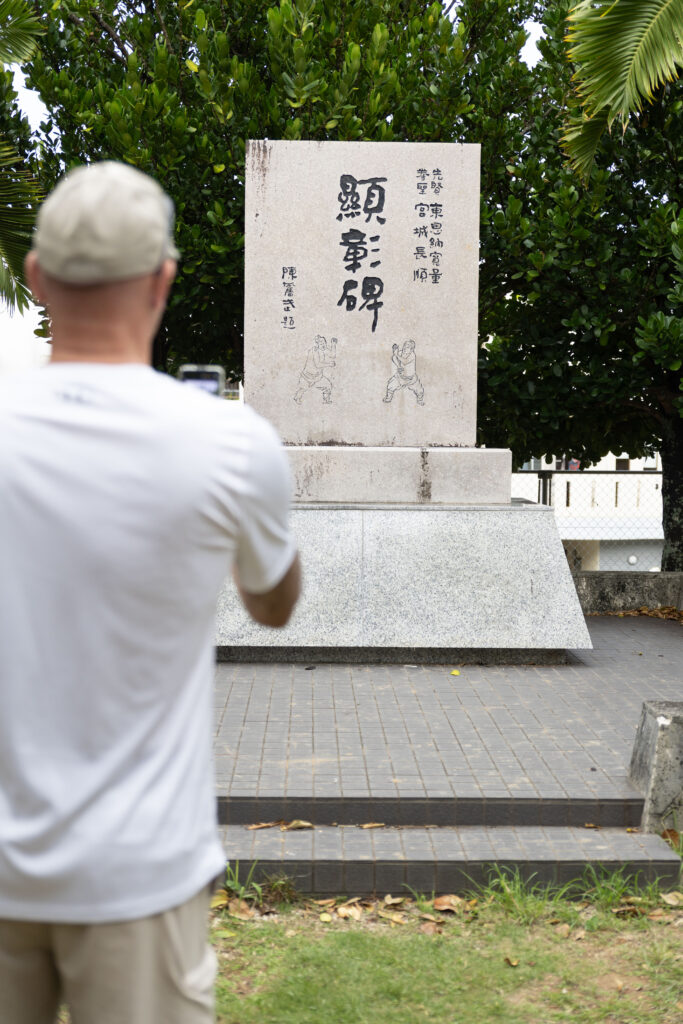 Visitor reading a stone karate monument in Okinawa