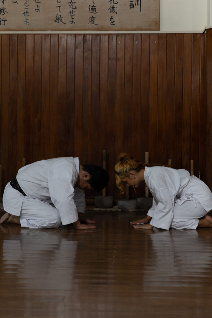 Two karateka bowing in seiza in a wooden dojo