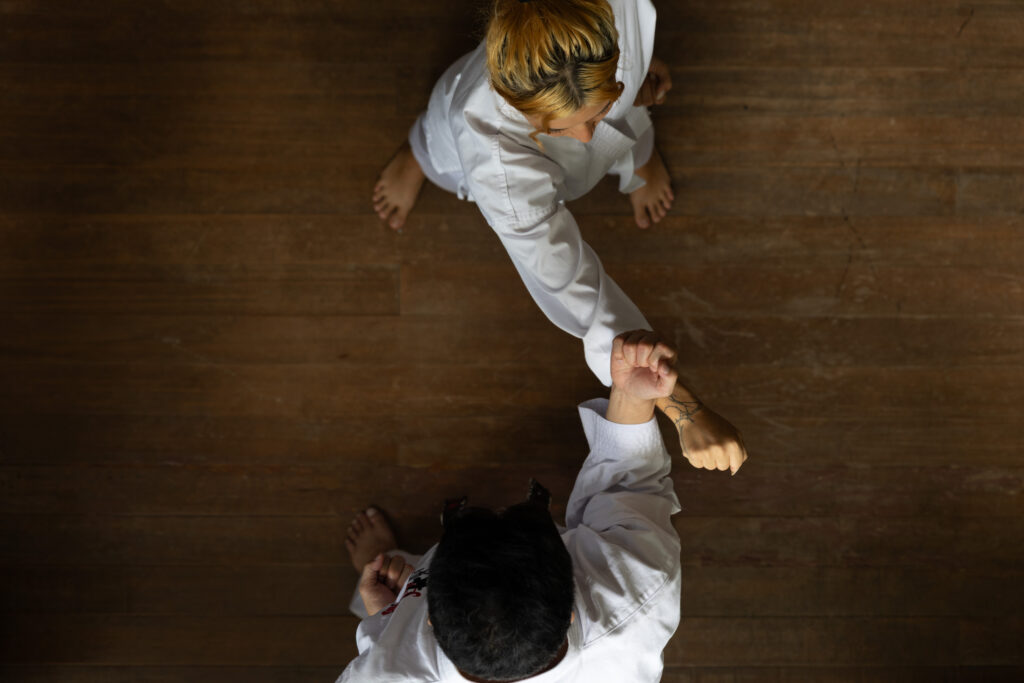 Two karateka practising a partner drill on a wooden floor, seen from above
