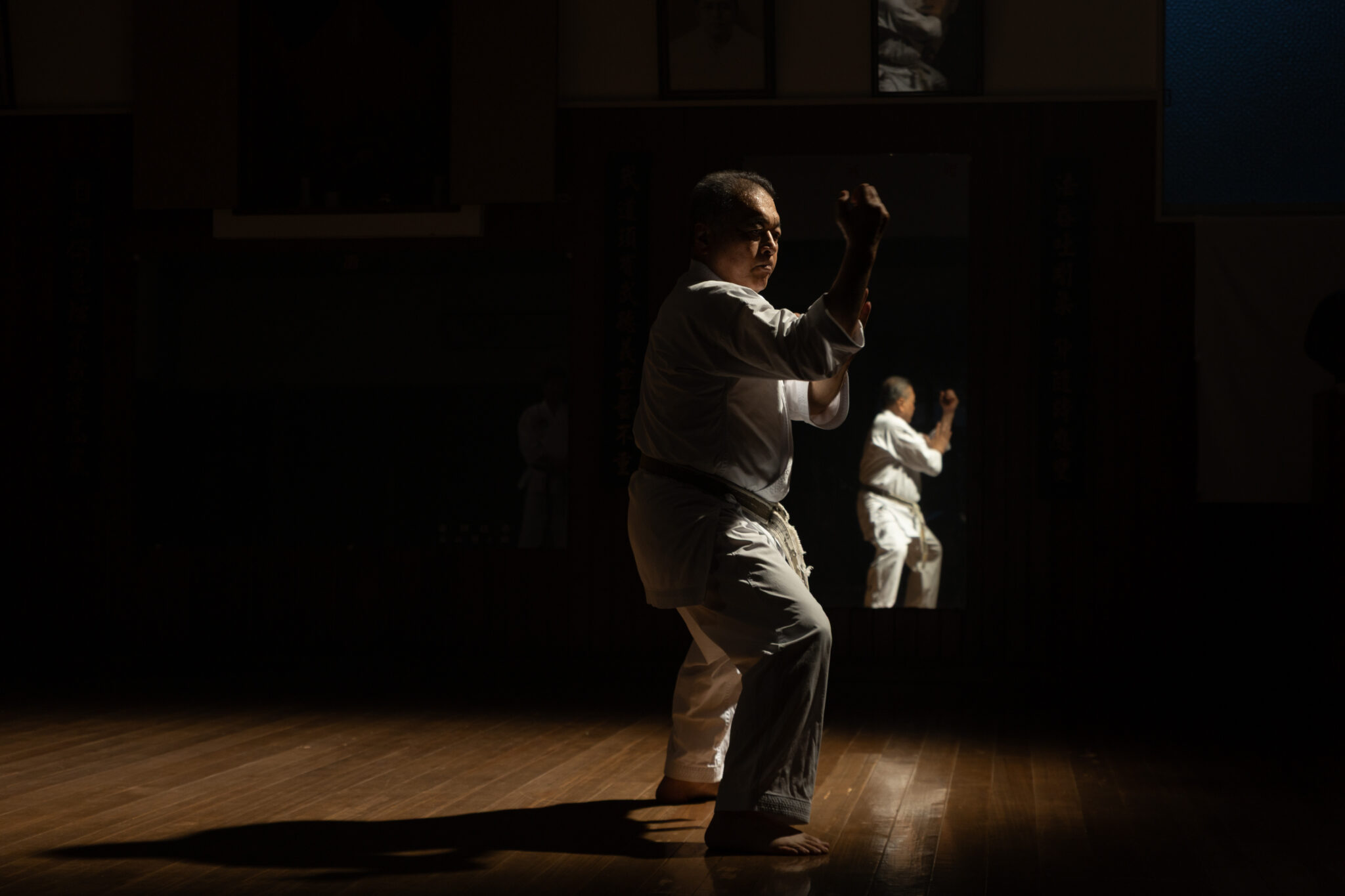 Karate master practising alone in a dimly lit dojo