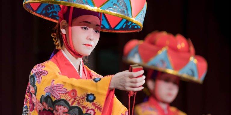 Okinawan dancers in traditional red costumes and hats