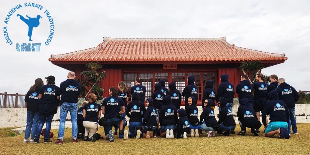 Łódzka Akademia Karate Tradycyjnego group in front of a red-roofed Okinawan dojo