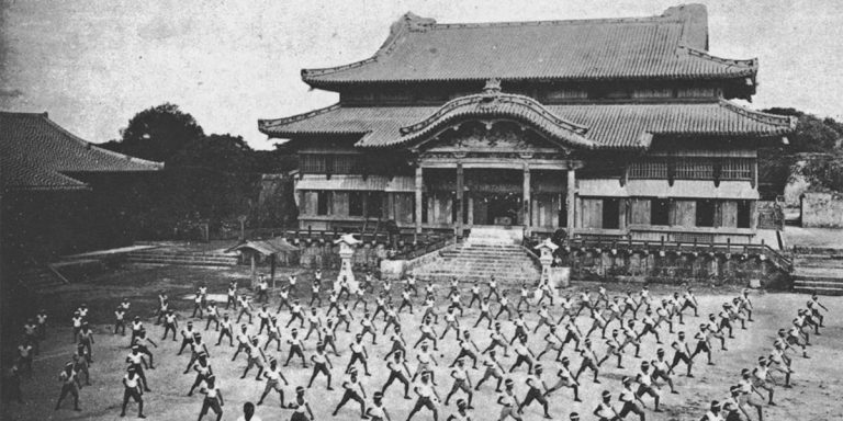 Historic photo of a mass karate demonstration in front of Shuri Castle