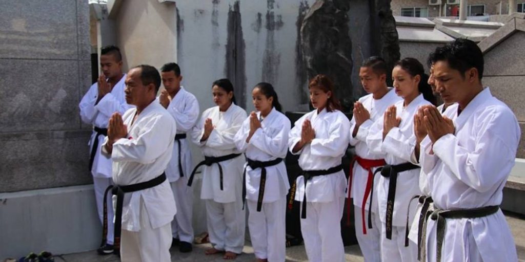 Nepal karate team bowing at a monument on a history tour