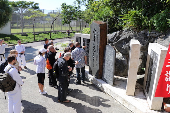 Visitors at the stone monument of Gichin Funakoshi at Okinogu Shrine