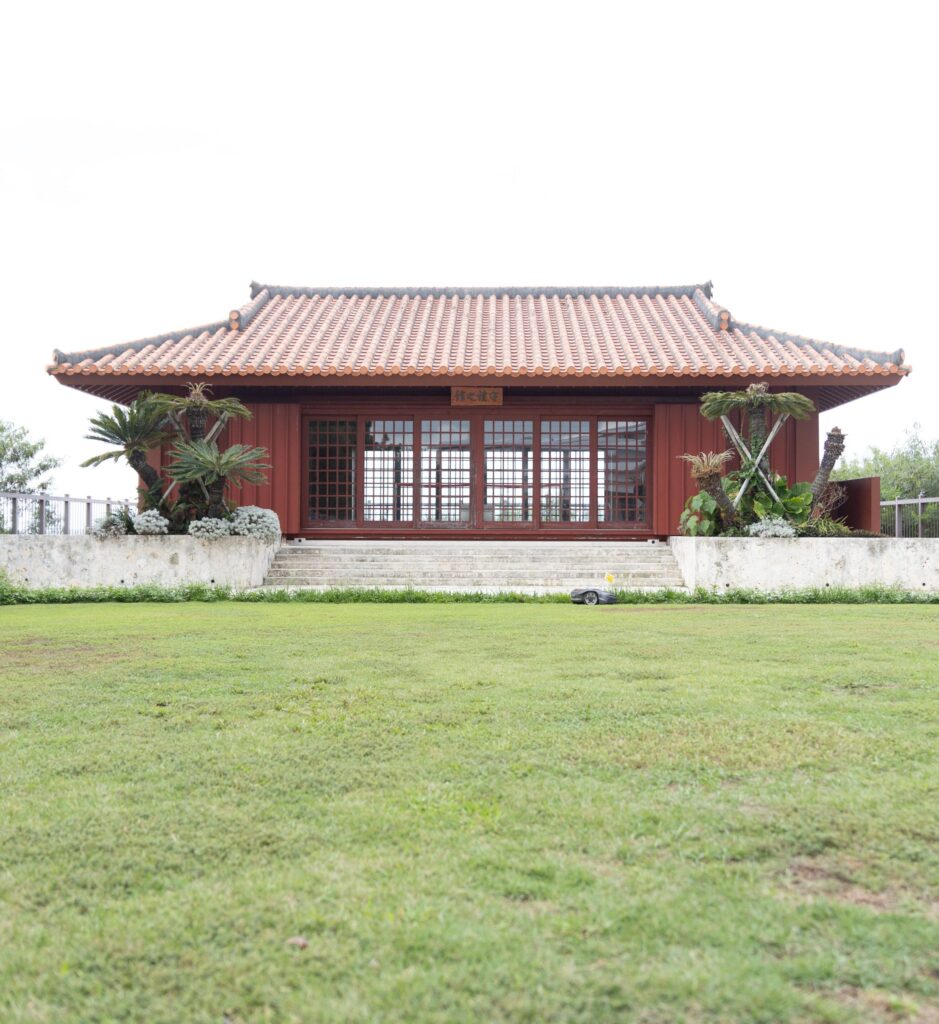 Traditional red-roofed Okinawan hall above a lawn