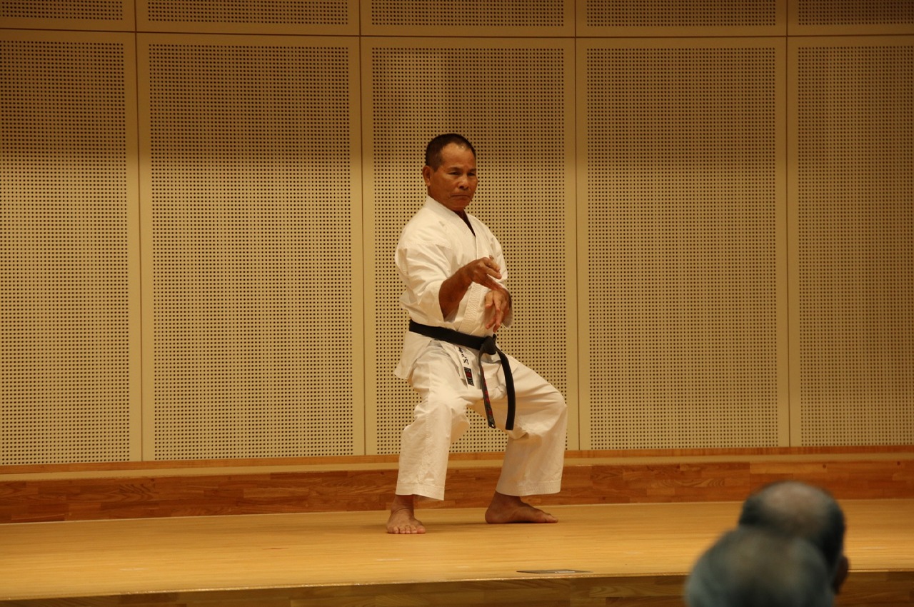 A karateka performing kata on a wooden dojo floor