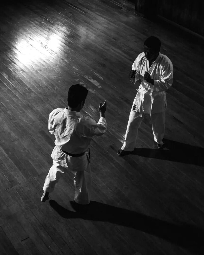 Two karateka sparring on a dojo floor