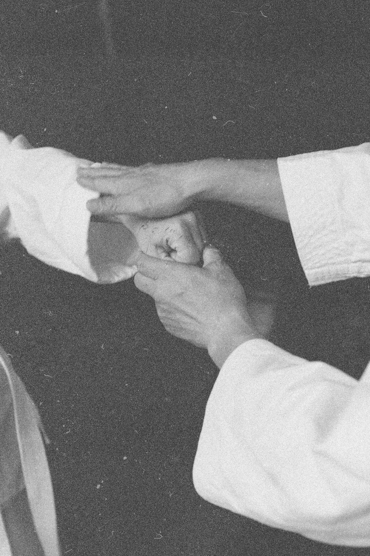 Black-and-white close-up of hands adjusting a white karate gi