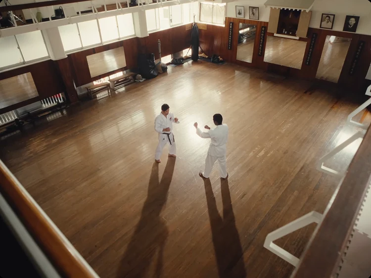 Two karateka training in an empty wooden dojo, seen from above
